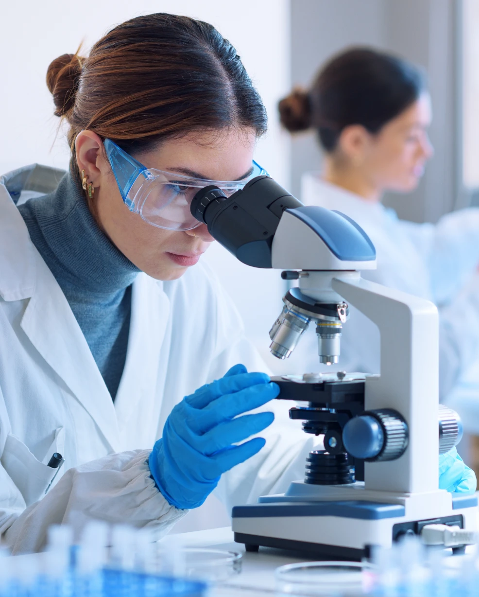 Young scientists conducting research investigations in a medical laboratory, a researcher in the foreground is using a microscope